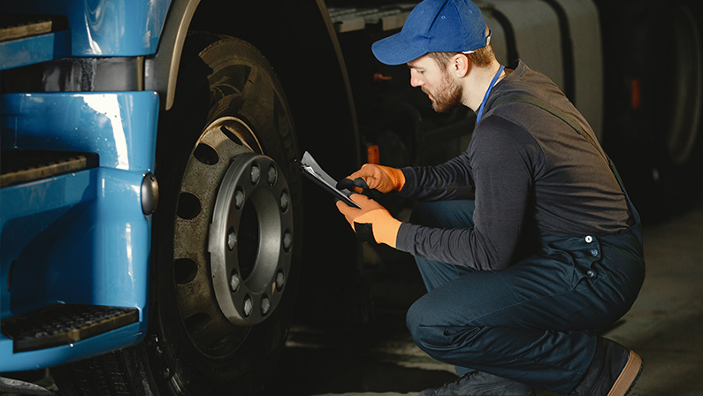 Man in Blue Cap Repairing Blue Truck's Wheel