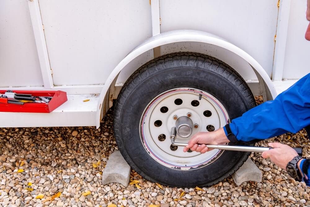 Homeowner works to remove a wheel from a utility trailer